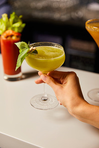 selective focus of woman touching margarita glass with cocktail