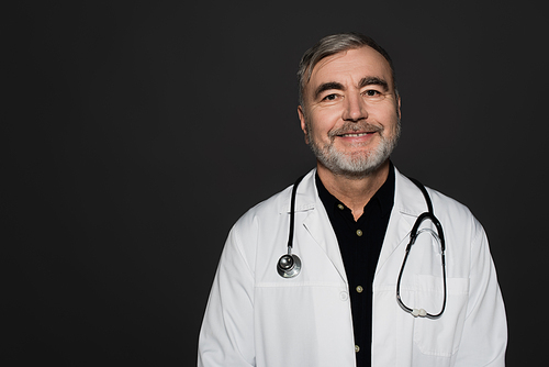 smiling bearded doctor with stethoscope  isolated on black