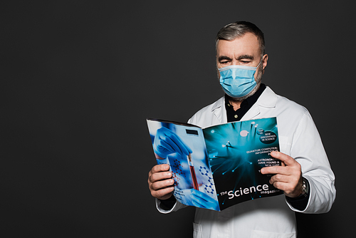 senior physician in medical mask reading science magazine isolated on dark grey