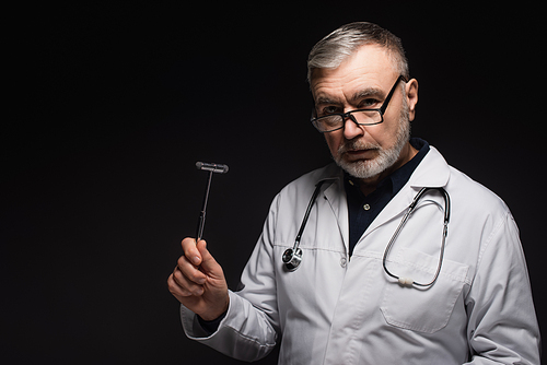 senior neurologist in eyeglasses holding reflex malleus and  isolated on black