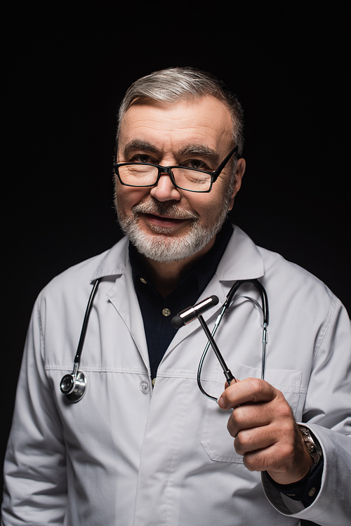 positive neurologist in white coat and eyeglasses holding reflex malleus isolated on black
