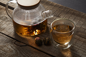 transparent teapot and glass with chinese blooming tea on wooden table