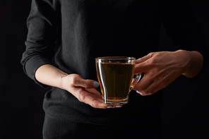 cropped view of young woman holding transparent cup of green tea isolated on black