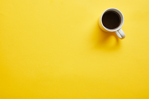 Top view of cup of hot delicious coffee on yellow background
