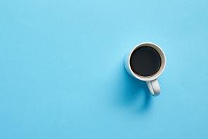 Top view of cup of hot coffee on blue background