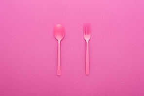 pink plastic spoon and fork isolated on pink