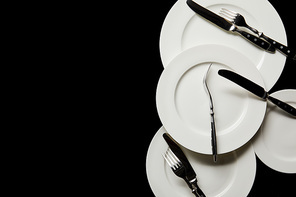 top view of white round plates with cutlery isolated on black with copy space