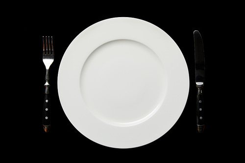 top view of white empty round plate and knife with fork isolated on black