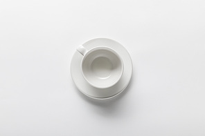 top view of empty white cup on saucer on white background