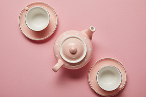 Pastel pink dotted teapot and cups with saucers on pink background