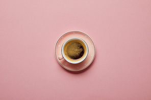 Cup of aromatic coffee at pink saucer with white dots on pink background