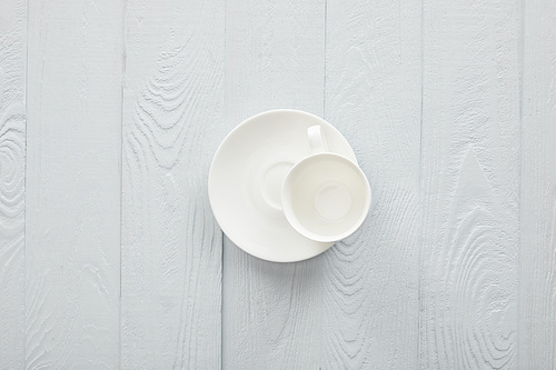 Empty white cup with saucer on white wooden surface