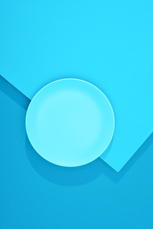 top view of empty plate on colorful blue surface