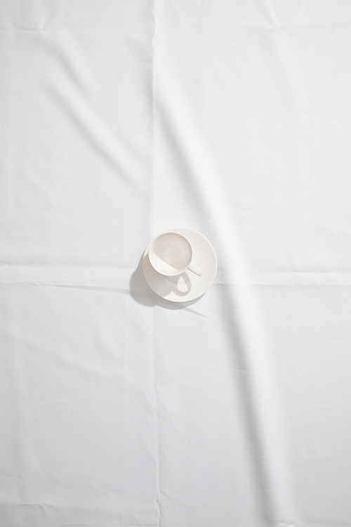 Top view of clean coffee cup on white cloth with copy space