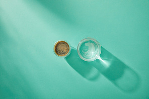 Top view of clear water and coffee in glasses on turquoise background with copy space