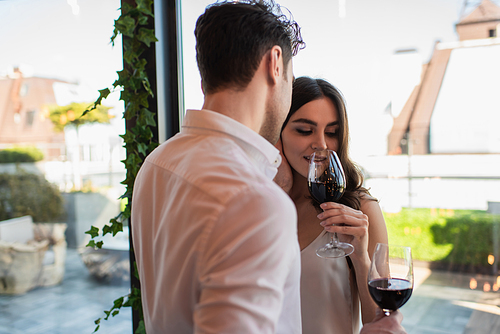 young woman drinking red wine near boyfriend