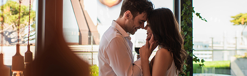 side view of man and woman smiling while hugging in restaurant, banner