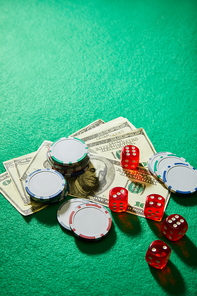 High angle view of dollar banknotes, dice and casino chips on green background