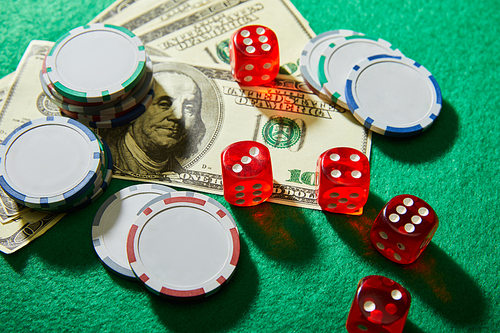High angle view of dollar banknotes, dice and casino chips on green