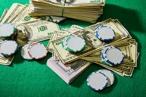High angle view of dollar banknotes and casino chips on green background