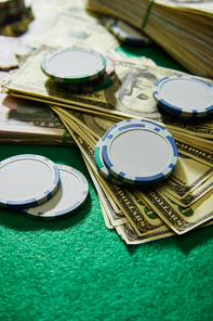 Selective focus of dollar banknotes and casino chips on green background