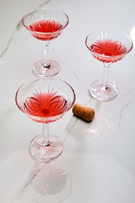 High angle view of glasses of cocktail near cork on white background