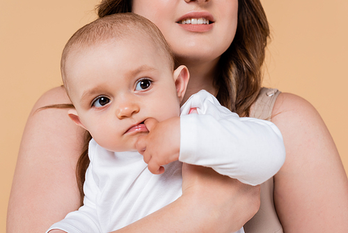 Plus size woman holding baby daughter isolated on beige