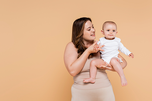 Happy plus size woman holding hand of child isolated on beige