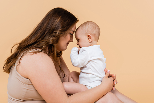 Side view of woman with overweight holding baby daughter isolated on beige