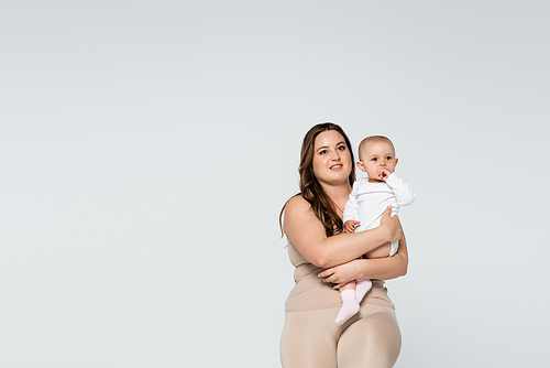 Happy woman with overweight holding child isolated on grey