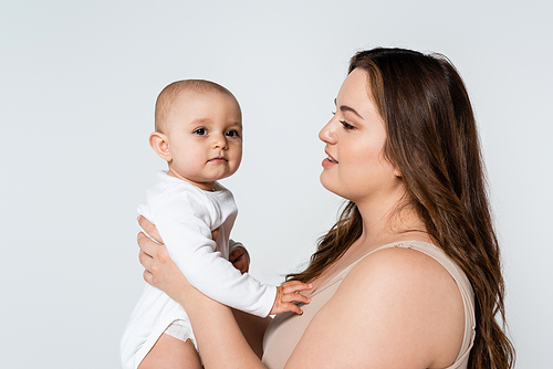 Young plus size parent looking at baby daughter isolated on grey