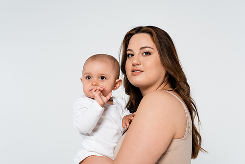 Pretty body positive woman hugging baby girl and  isolated on grey