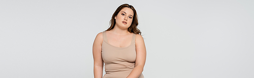 Young body positive woman  isolated on grey, banner