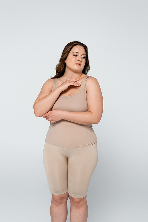 Young body positive woman touching chest isolated on grey