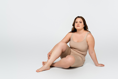 Young body positive woman  while sitting on grey background
