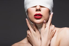 woman in elastic bandage, bare shoulders and red lips isolated on grey