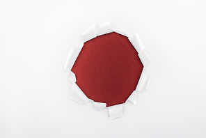 ragged hole in textured white paper on burgundy background