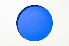 cut out round hole in white paper on electric blue colorful background