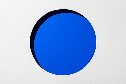 cut out round hole in white paper on electric blue background