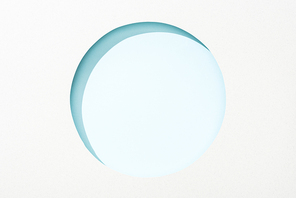 cut out round hole in white paper on light blue background