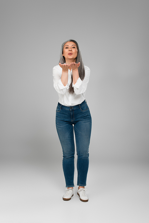 full length view of middle aged woman in jeans and white shirt