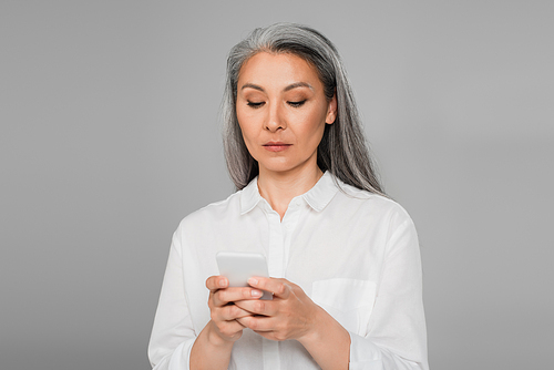 serious mature woman messaging on mobile phone isolated on grey