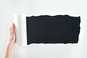 cropped view of woman holding textured white paper with rolled edge on black background
