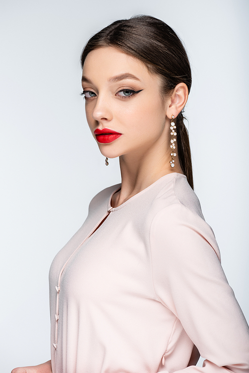 pretty woman in earrings and blouse  while posing isolated on grey