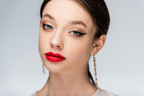 pretty young woman in earrings with red lips  isolated on grey