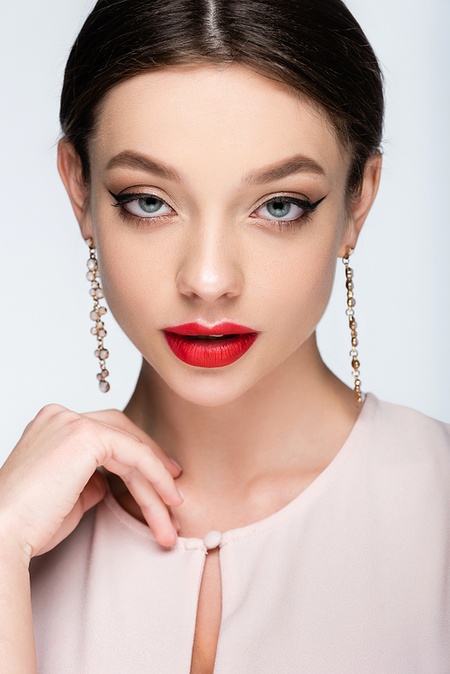young and pretty woman in earrings posing isolated on grey