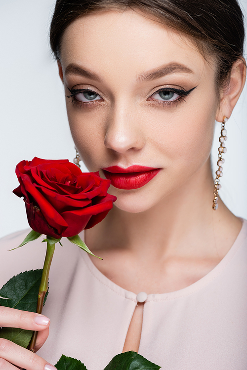 pretty woman in earrings holding red rose isolated on grey