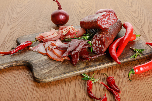 delicious meat platter served with chili pepper and rosemary on wooden table