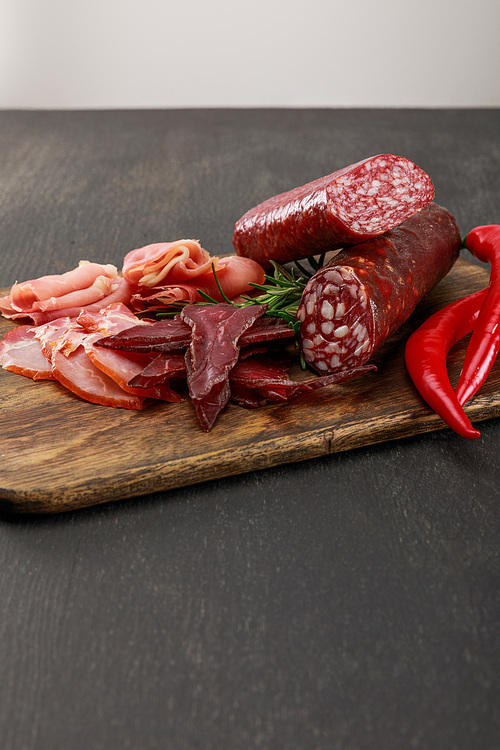 delicious meat platter served with chili pepper and rosemary on wooden black table
