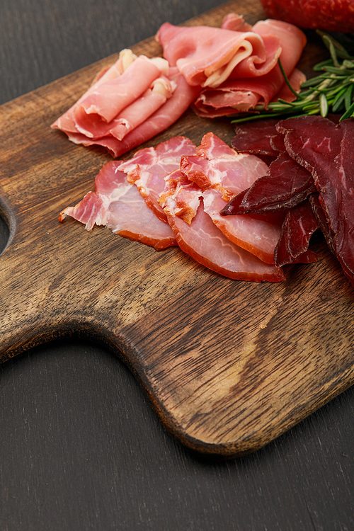close up view of delicious meat platter served with rosemary on wooden black table